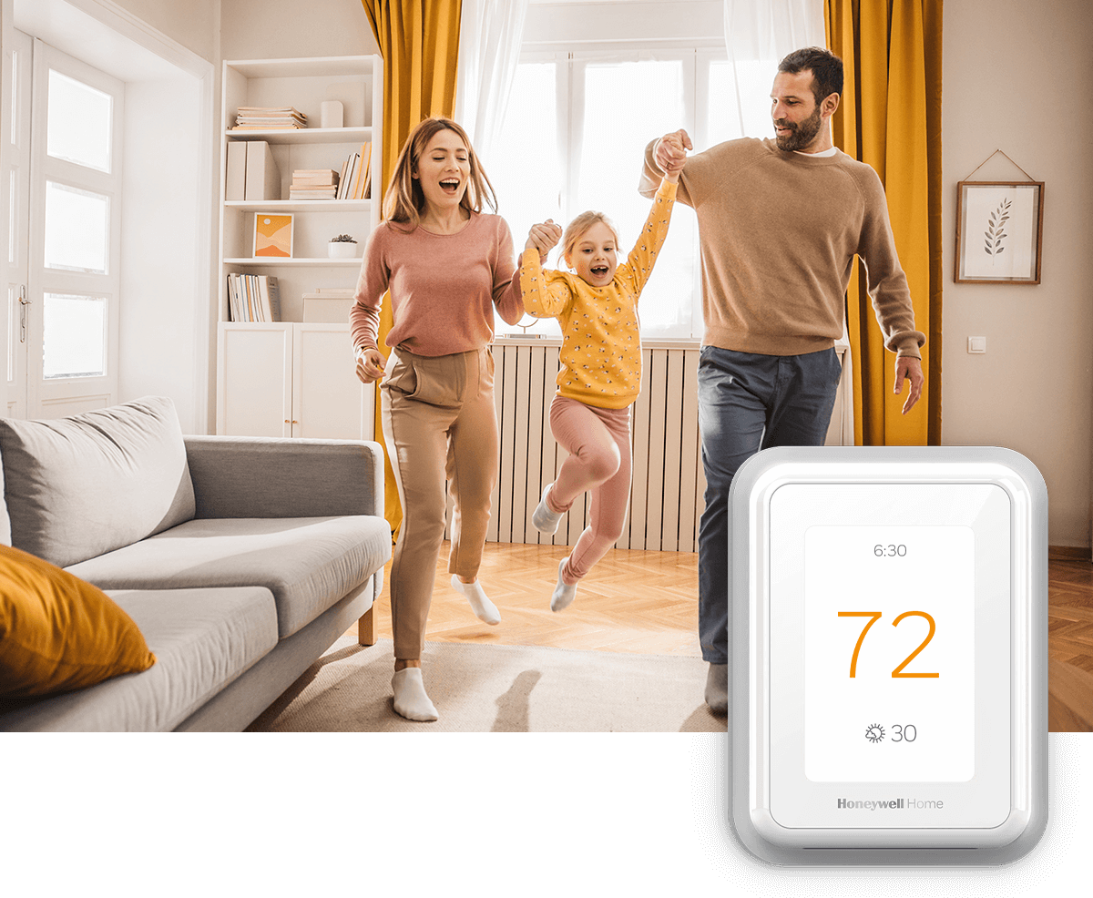 A young couple swings a child in the air of a bright living room; a thermostat image is in the foreground