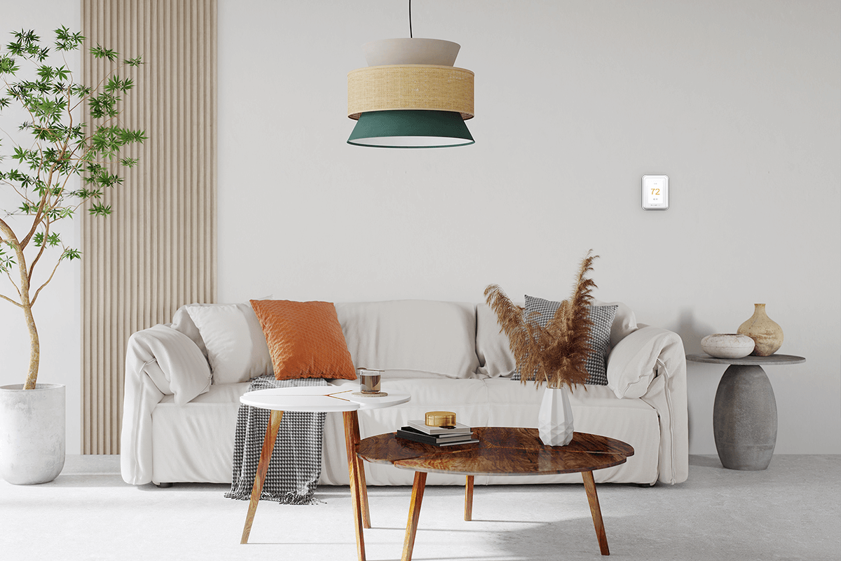  A cozy living room with pillows on a sofa, artwork, and a wall thermostat