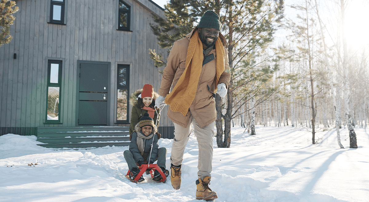 An older couple sits outside on the steps of a house, happily greeting young children climbing stairs