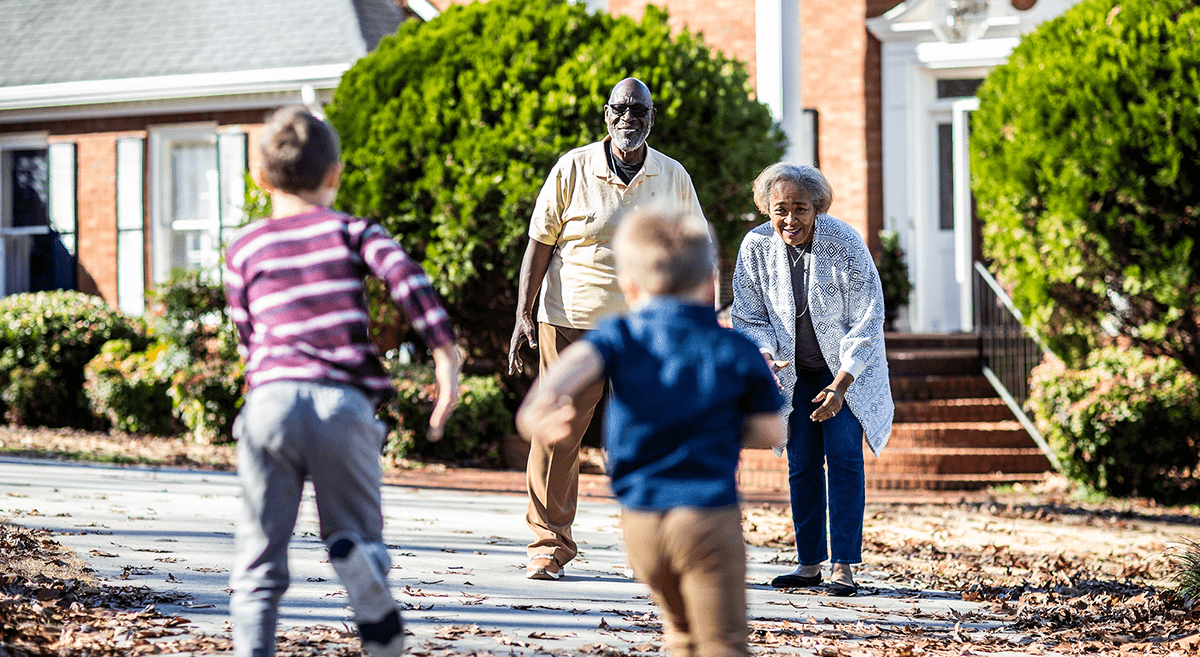 An older couple greet children running in a suburban neighborhood