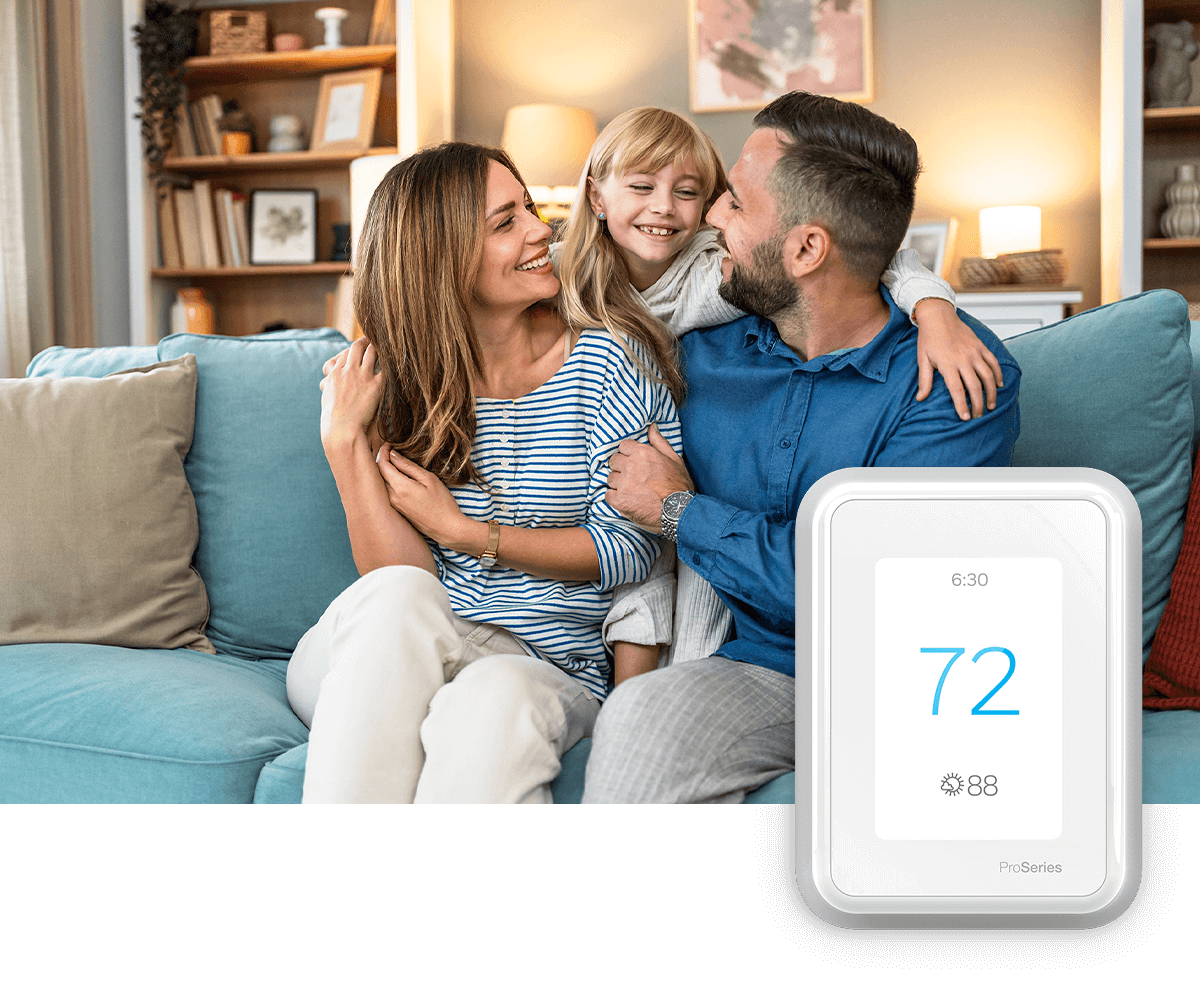 A happy young family sits on couch smiling; a thermostat image is in the foreground