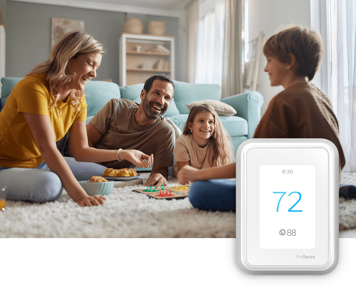 A mother and her daughter laugh on a sofa in a bright room; a thermostat image is in the foreground