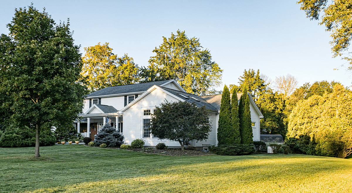 A white house in a suburban setting with green grass and trees