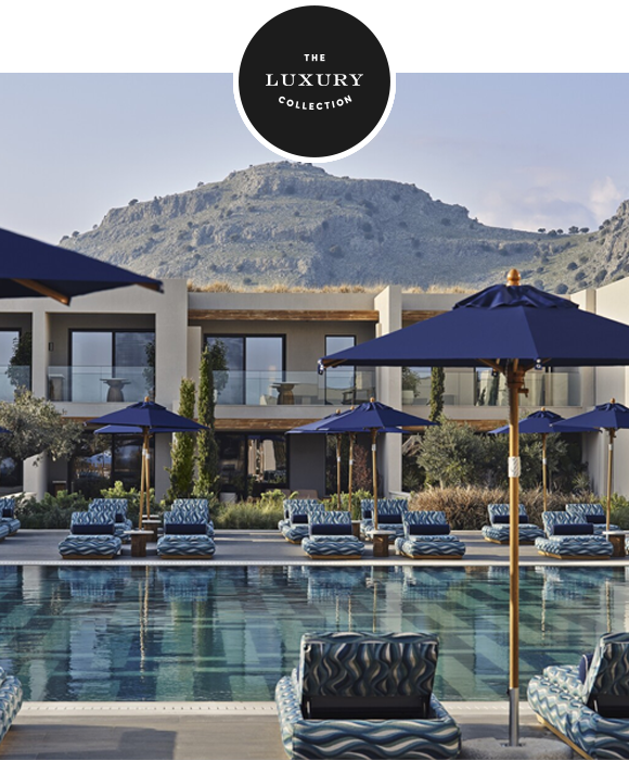 View of the pool at Amoh, a Luxury Collection Resort, Rhodes with villas, umbrellas, and mountain backdrop.