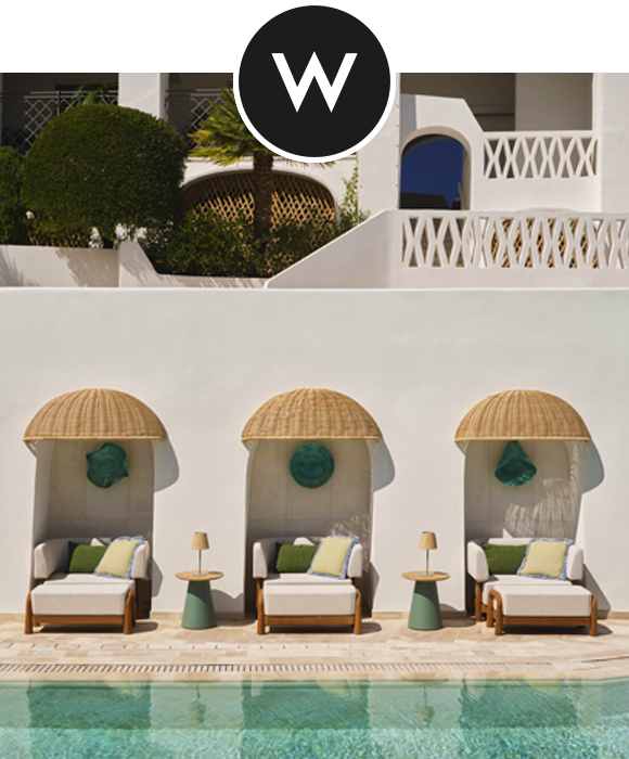 Lounge chairs under woven canopies by the pool at W Sardinia - Poltu Quatu, set against a white Mediterranean-style building with greenery.