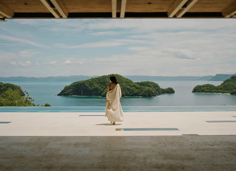 A woman standing on a rooftop overlooking the nature of Costa Rica at Nekajui, a Ritz-Carlton Reserve.