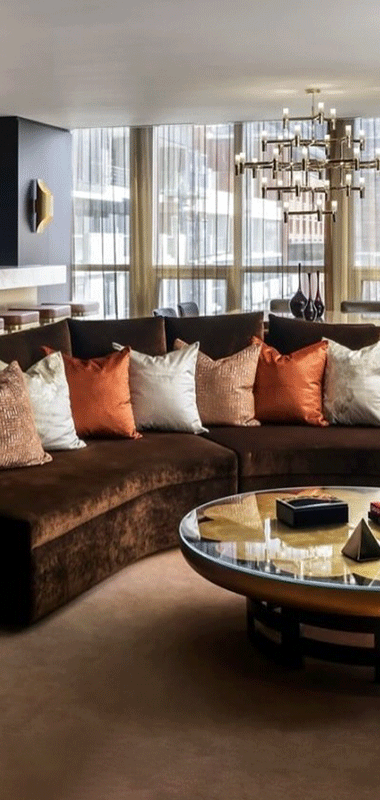 Hotel suite with a velvet couch with a row of jewel-toned pillows.