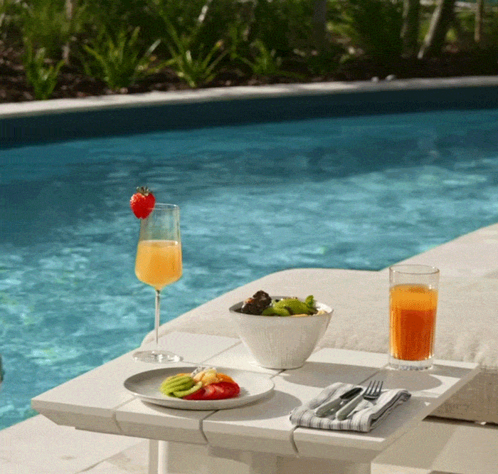 Animated GIF of a pool floaty gliding across a pool with a colorful breakfast in the foreground.