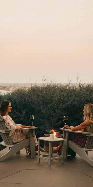 Two women enjoying wine by a beach with imagery of cookout meals.
