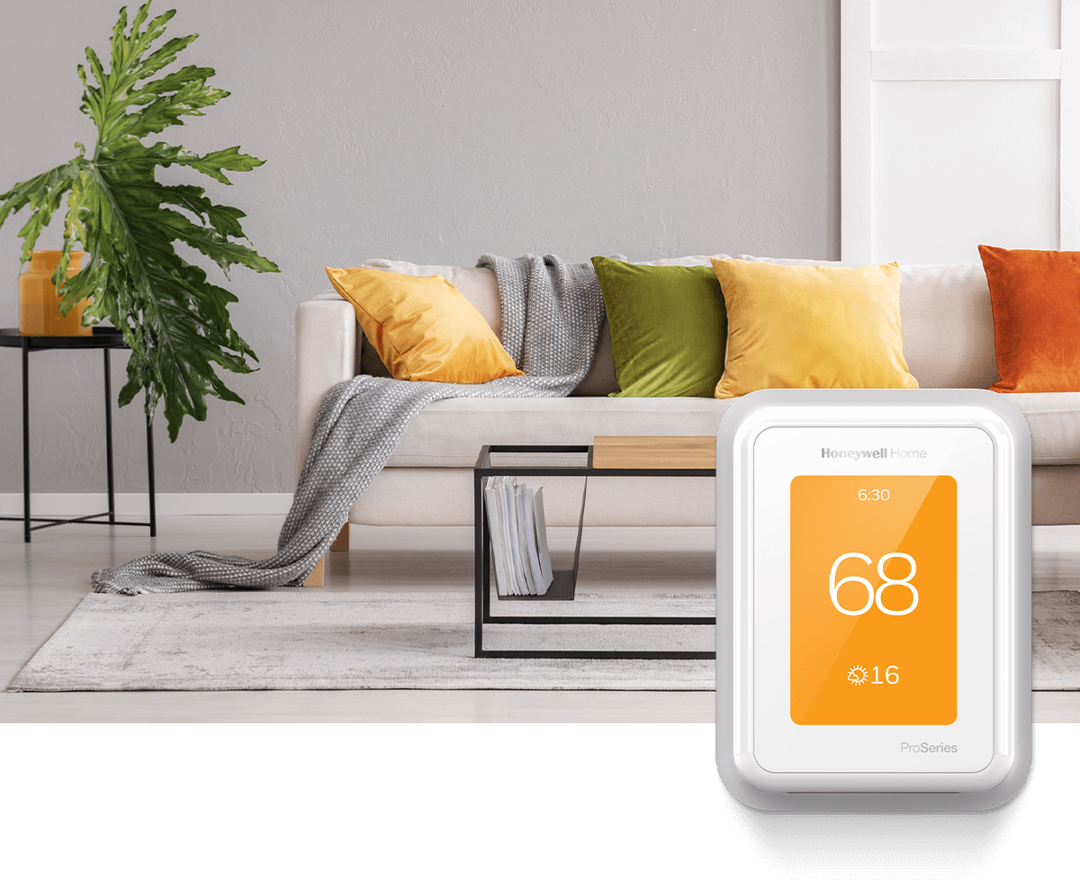 A modern living room adorned with orange, yellow, green and gray colors; in the foreground is a white Honeywell Home thermostat displaying 70 degrees.