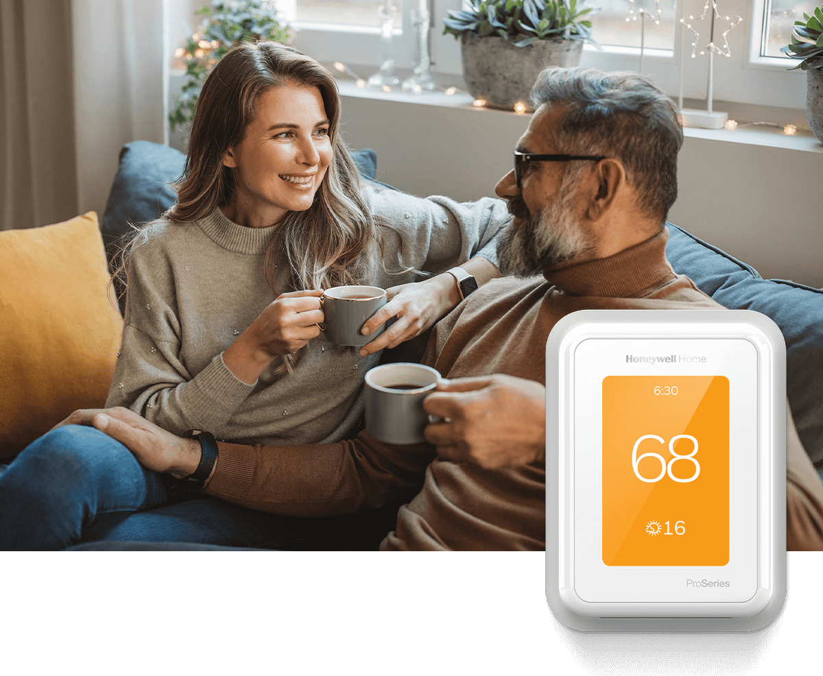 A couple enjoys coffee on a sofa together, while a Honeywell Home thermostat in the foreground displays 70 degrees.