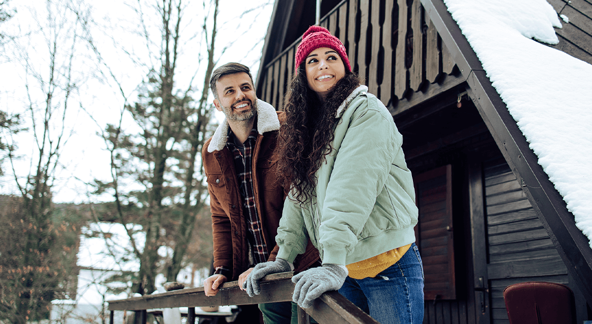 A couple enjoys a moment together just outside of their cabin in the woods.