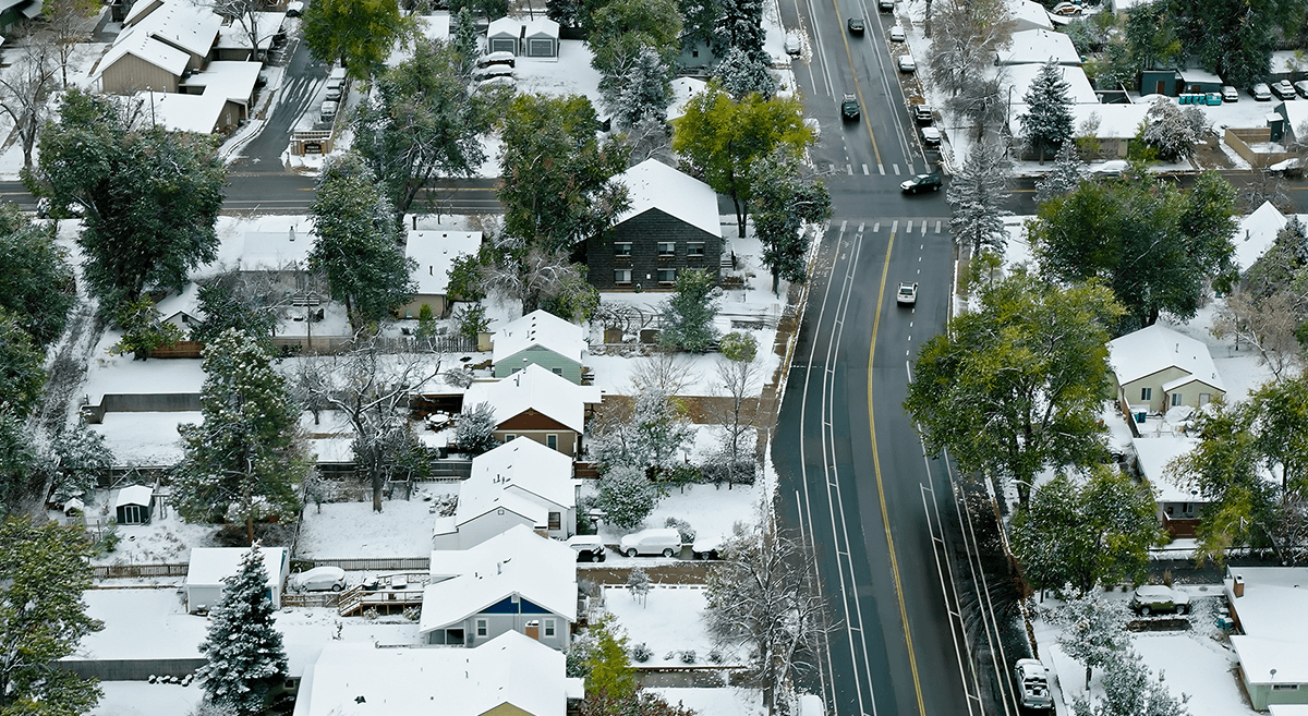 An aerial view of a suburban street with snow on the ground.