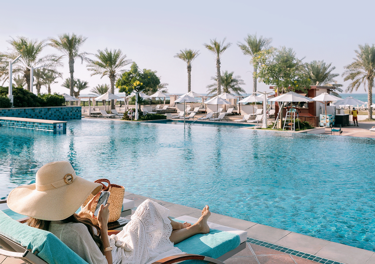 A woman sitting poolside at the St. Regis Doha.