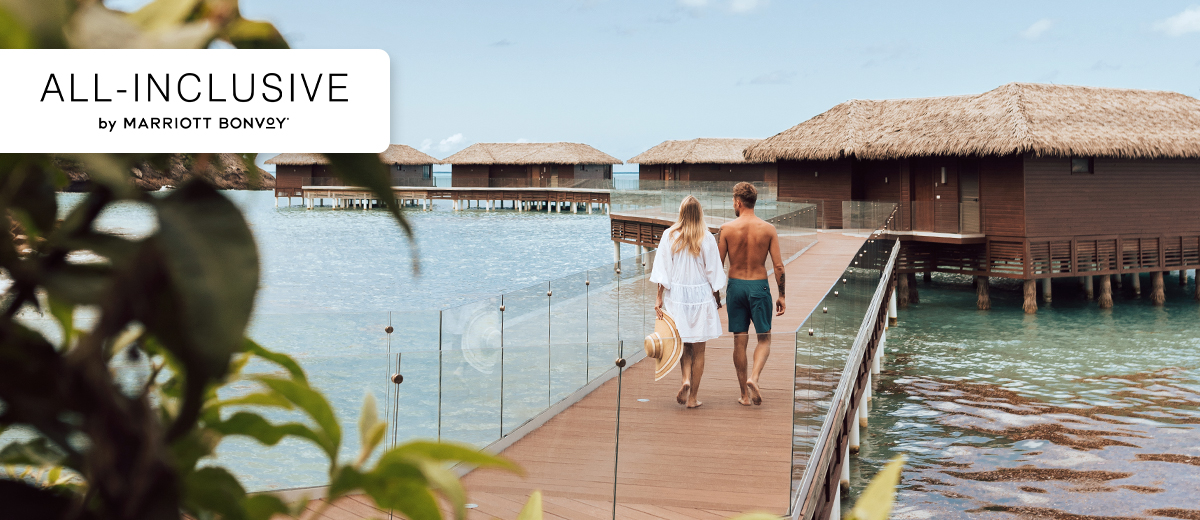 Couple walking along a dock at an All-Inclusive by Marriott Bonvoy hotel.