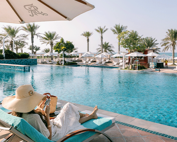 Woman sitting poolside on a sunny day.