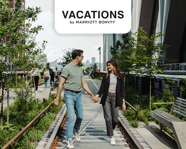 A couple walking around New York City, enjoying both the trees and skyscrapers.