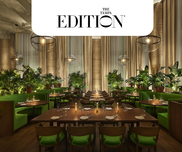 View of the Lilac at The Tampa EDITION. The restuarant has wooden tables with green chairs and booths, and many plants decorating the space.