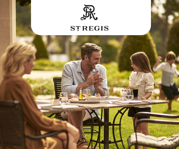 A family enjoying a meal outside. The father and daughter talk, while the son plays in the background.