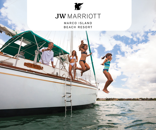 A family enjoys riding a boat out in the water. The two daughters are jumping off the side of the boat into the water.