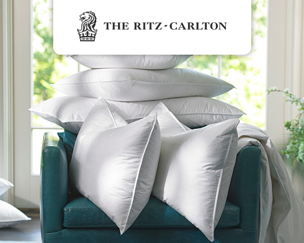 Ritz-Carlton Pillows piled up on a green sofa chair.