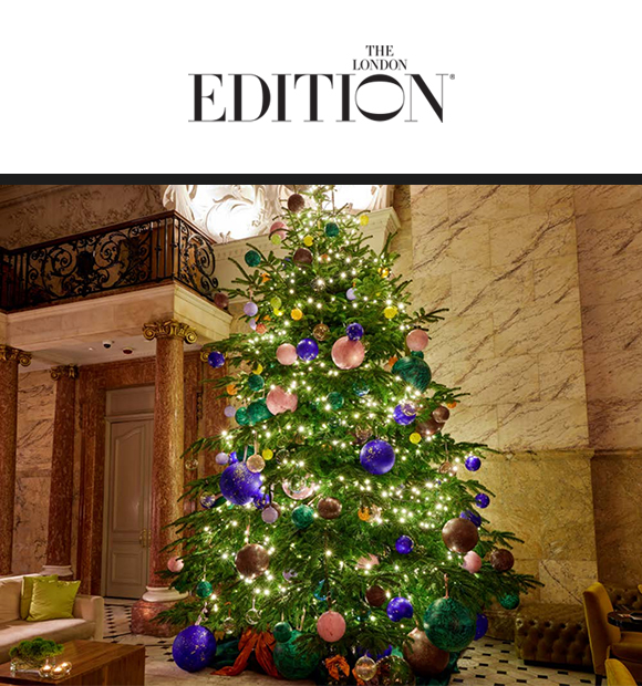 Elegant Christmas tree adorned with purple, pink, and green ornaments, glowing lights, set in a luxurious marble and columned lobby, festive ambiance.