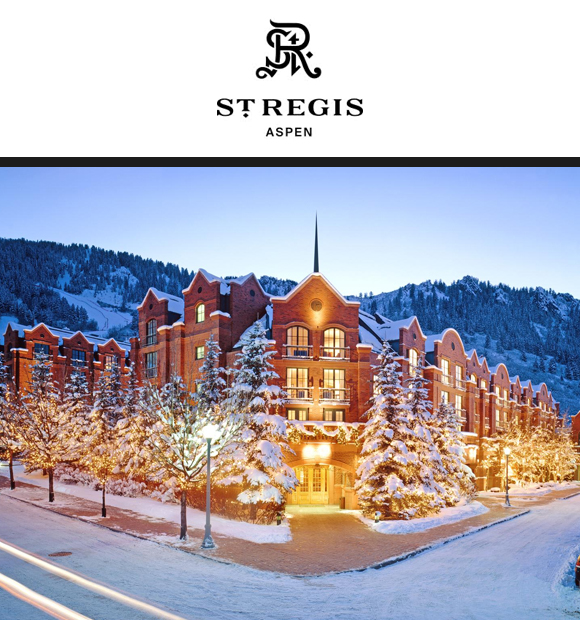 Majestic winter view of St. Regis Aspen, a luxurious brick hotel with snowy trees and mountains.