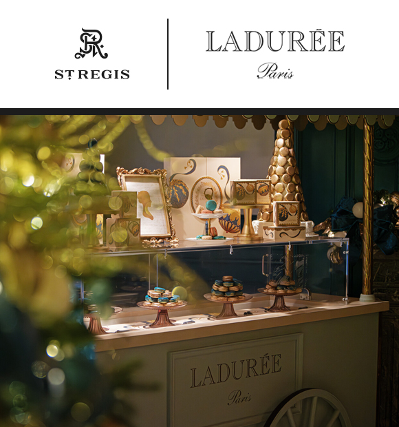Elegant Ladurée pastry display features colorful macarons on stands, framed artwork, and gold decor under soft light.