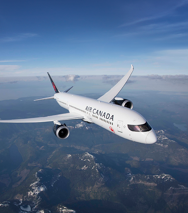 An Air Canada airplane is flying through the sky.