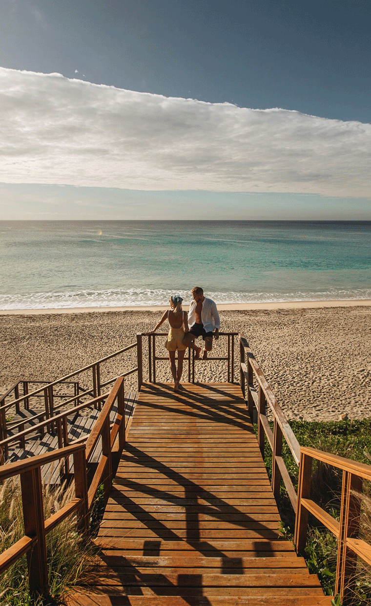 A couple at the end of a boardwalk on a beach.