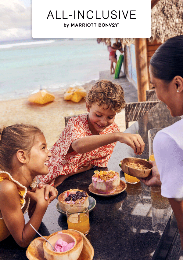 Children eating smoothie bowls on a beach.