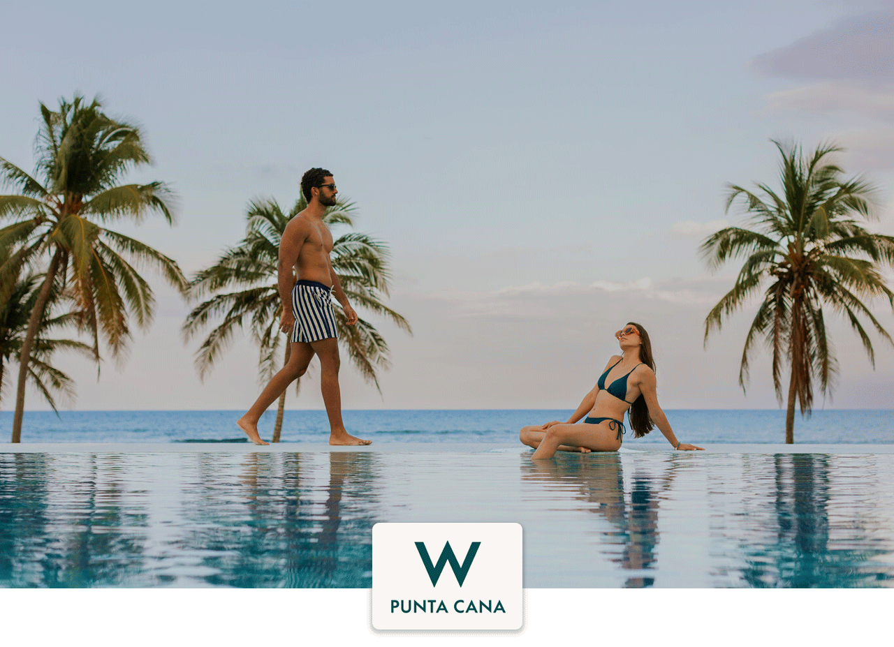 A man and woman lounging in a pool overlooking the beach with palm trees at W Hotels, Punta Cana.