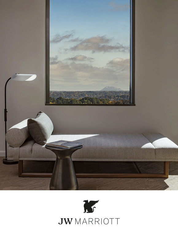 A minimalist room with a soft gray chaise lounge next to a window showcasing a scenic view.